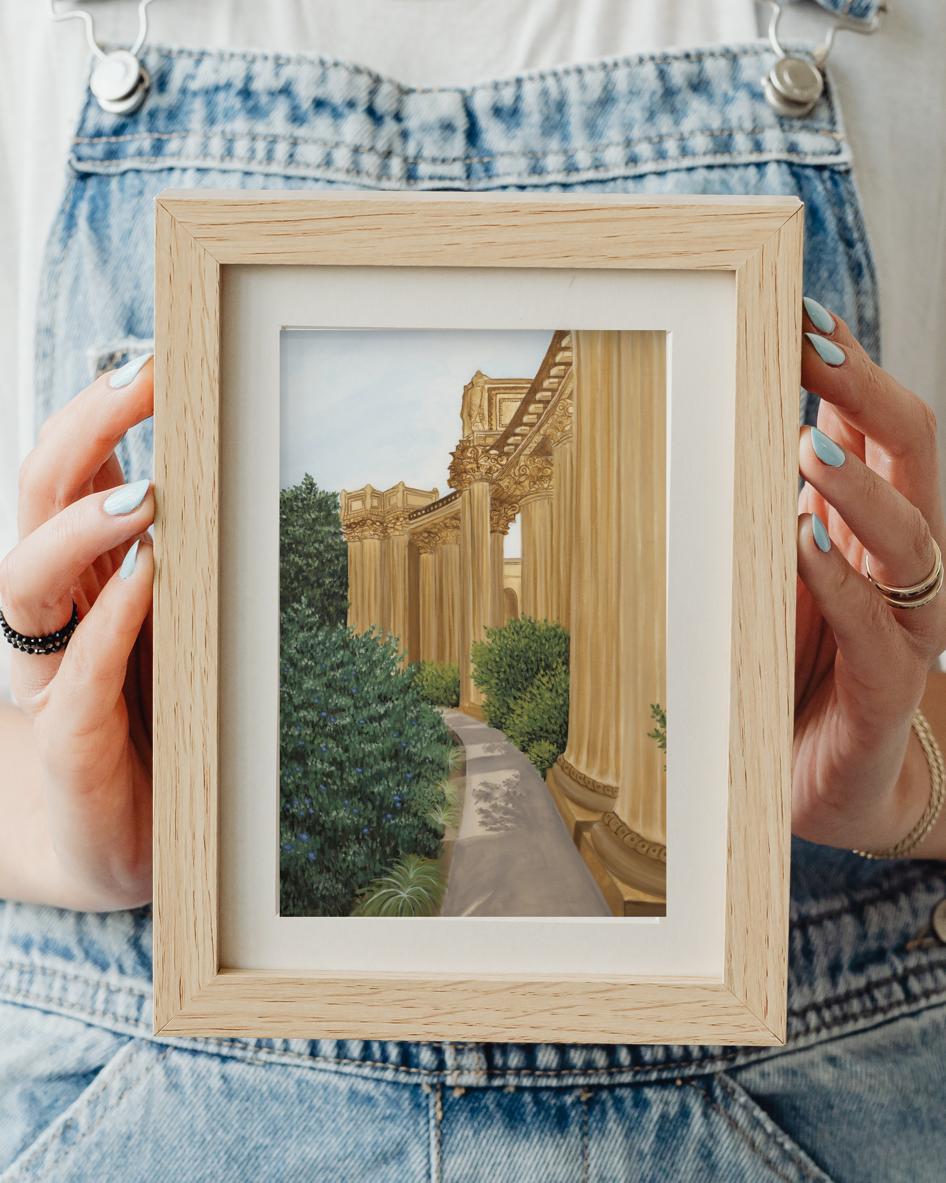 Person holding a small framed artwork of a classical building with columns and greenery fine art print for sale