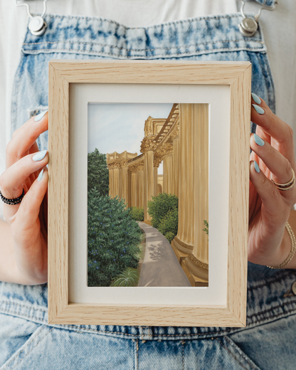 Person holding a small framed artwork of a classical building with columns and greenery fine art print for sale