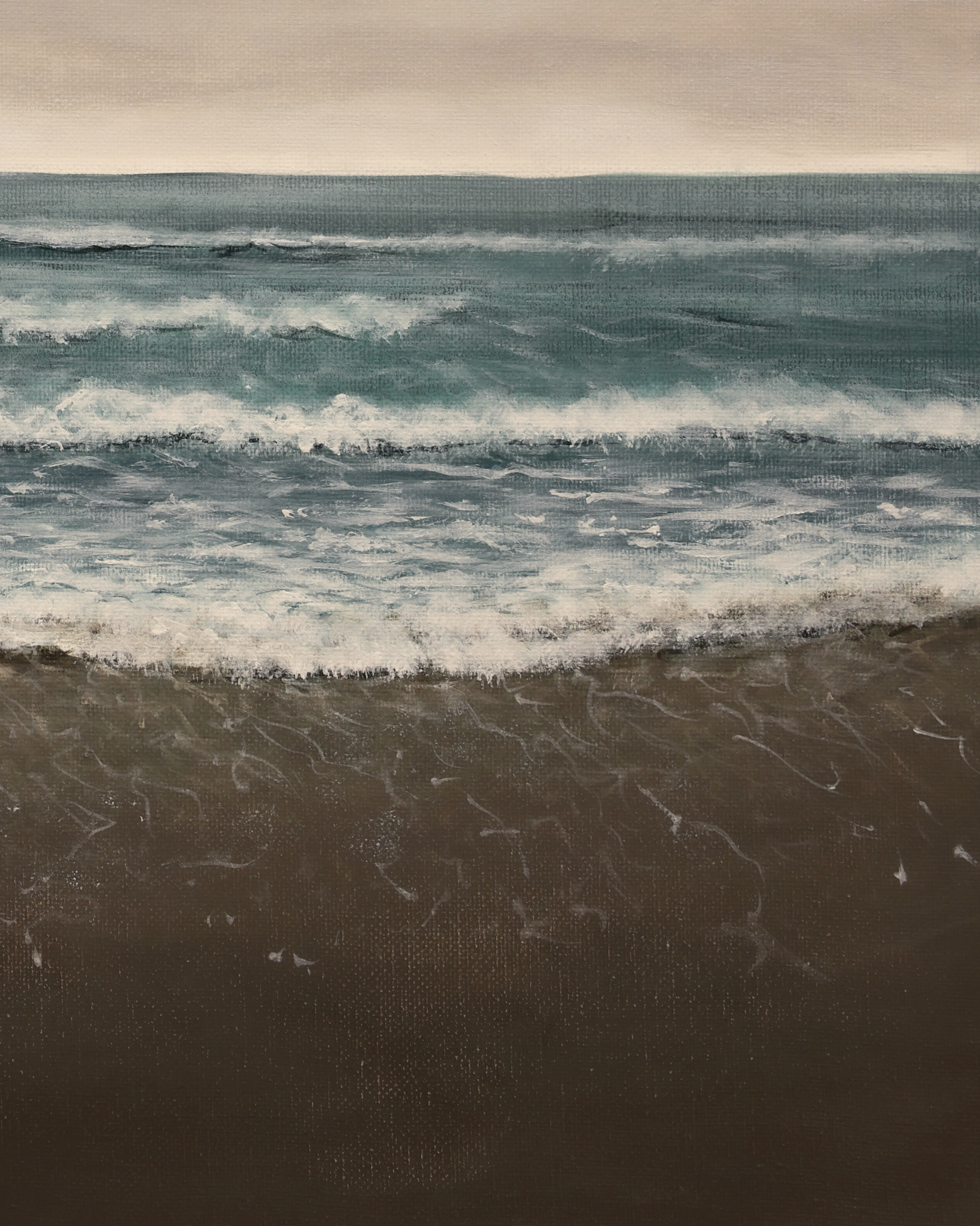 Waves crashing onto a beach with a cloudy sky above.